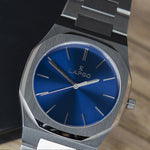 Reloj plateado con 3 manecillas y dial azul