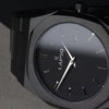 Reloj negro con 2 manecillas plateadas y dial negro con fecha