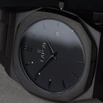 Reloj negro con 2 manecillas negras y dial negro con fecha